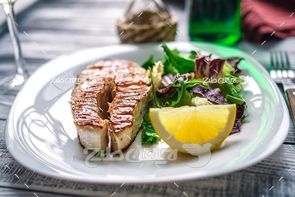 غذای کباب گوشت ماهی و لیمو و سالاد و سبزیجات، چنگال