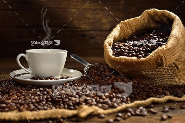 عکس قهوه داغ در فنجان سفید و دانه های قهوه